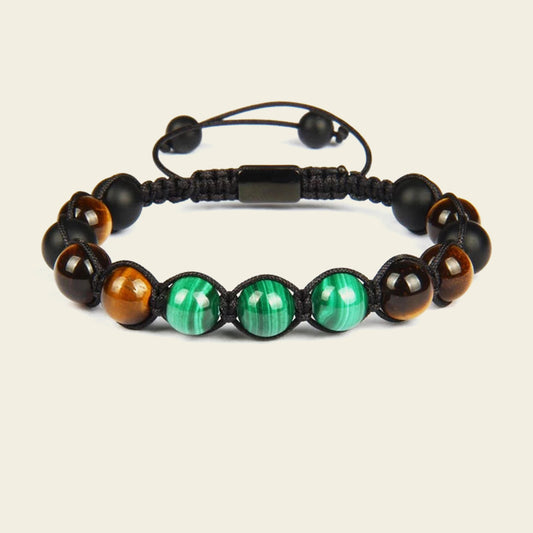 Bracelet with black, green, and brown beads on a beige background