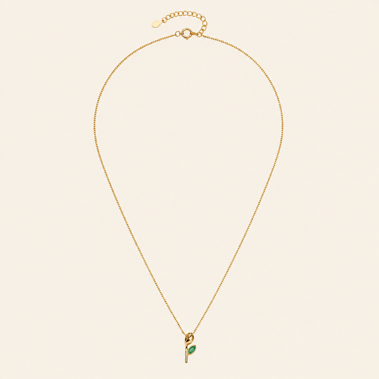 Gold necklace with a green pendant on a beige background
