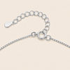 Close-up of a silver chain necklace showing the extender chain, clasp, and tag on a light beige background.