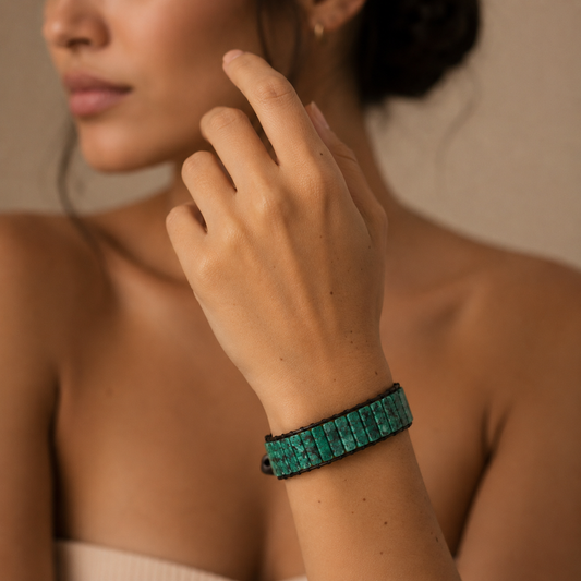Close-up of a person wearing a green bracelet on a neutral background