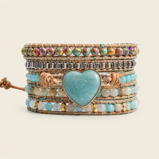 A stack of bohemian-style multi-layer bracelets featuring a large heart-shaped turquoise stone centerpiece, turquoise beads, iridescent beads, silver-toned metal charms, and brown cord wraps, set against a solid light beige background.