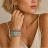 Woman wearing multiple bracelets on her wrist with a neutral background