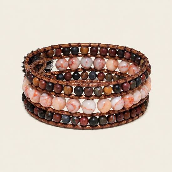 A stack of four copper wire bracelets wrapped with multi-strand beads in earthy brown, pink, white, and dark gray marbled stone, shown on a light beige background.