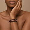 Close-up of a person wearing two beaded bracelets on a beige background