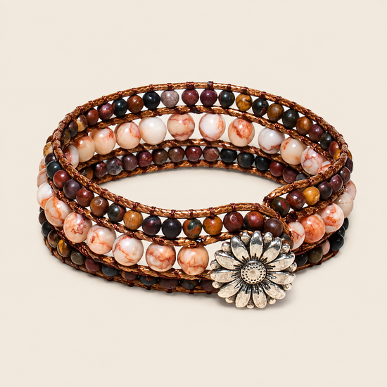 A multi-strand wrap bracelet featuring polished stone beads in earthy brown, cream, and marbled tones, accented by a silver-toned daisy flower charm, set against a solid light beige background.