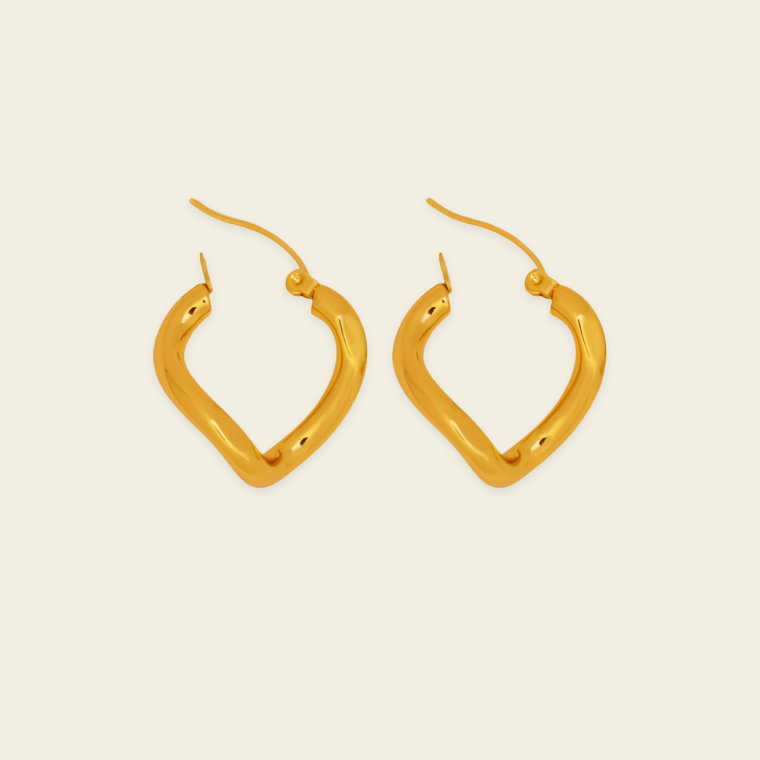 A pair of gold-toned, abstract open hoop earrings with curved, organic edges and fishhook backings, displayed on a solid, warm off-white background.