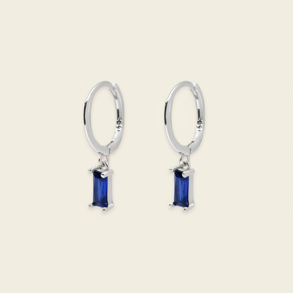 A pair of gold hoop earrings with rectangular blue gemstone drops, shown on a light beige background.