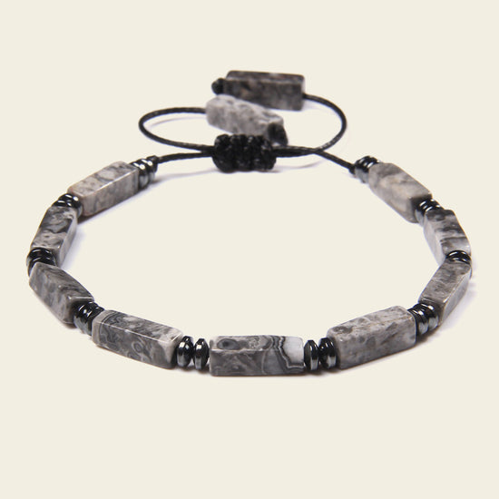 Gray beaded bracelet with black accents on a light beige background