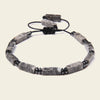 Gray beaded bracelet with black accents on a light beige background