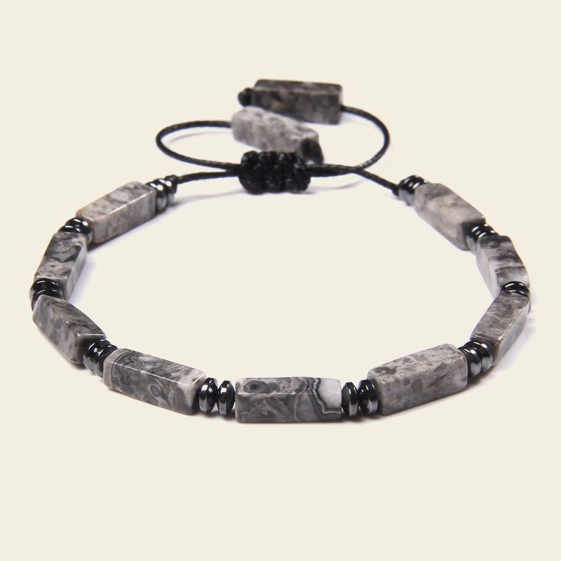 Gray beaded bracelet with black accents on a light beige background