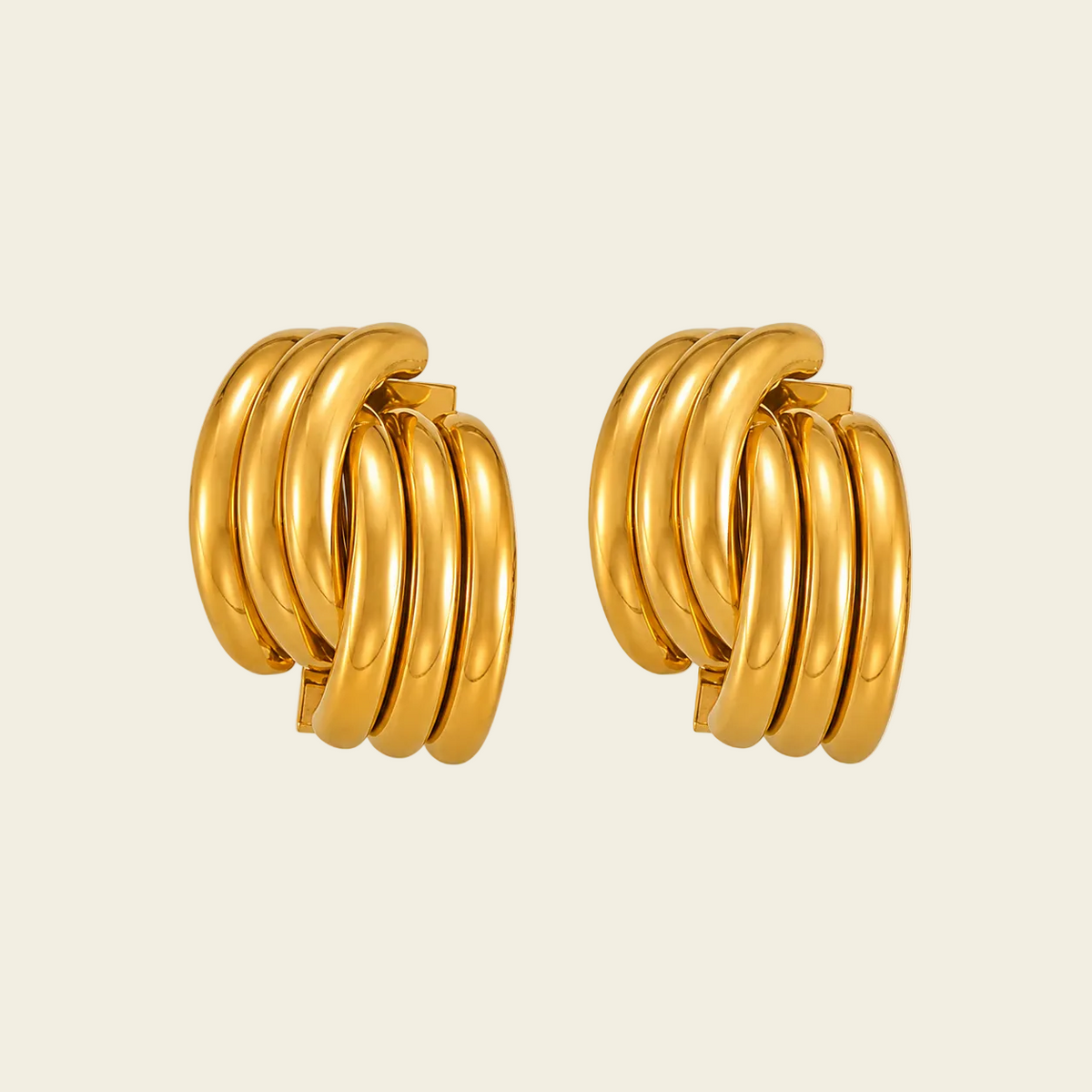 A pair of gold hoop earrings with a multi-layered, coiled design, shown on a solid light beige background.