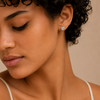 Close-up of a woman wearing a diamond earring against a beige background