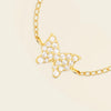 Gold butterfly necklace with clear stones on a beige background