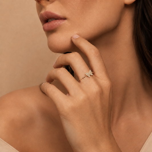 Close-up of a woman's hand wearing a gold ring with a diamond on a beige background