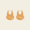 A pair of gold-toned, organic-shaped hoop earrings with a polished, reflective finish, displayed on a solid light beige background.