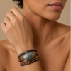 Woman wearing a stack of bracelets on her wrist against a neutral background