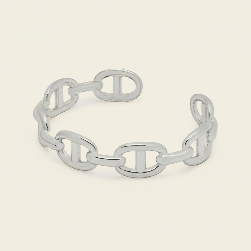 A chain-link cuff bracelet with a polished finish, displayed on a light beige background.