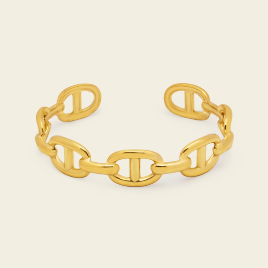 A polished gold chain-link cuff bracelet with interlocking oval links, shown on a clean off-white background.