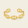A polished gold chain-link cuff bracelet with interlocking oval links, shown on a clean off-white background.