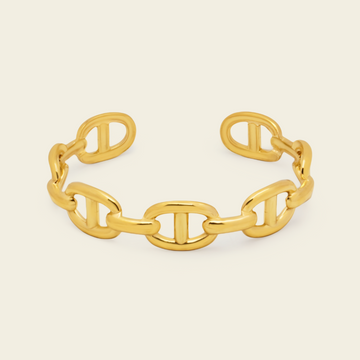A polished gold chain-link cuff bracelet with interlocking oval links, shown on a clean off-white background.