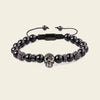 Black beaded bracelet with a skull charm on a beige background