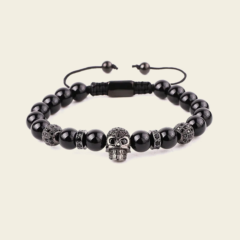 Black beaded bracelet with a skull charm on a beige background