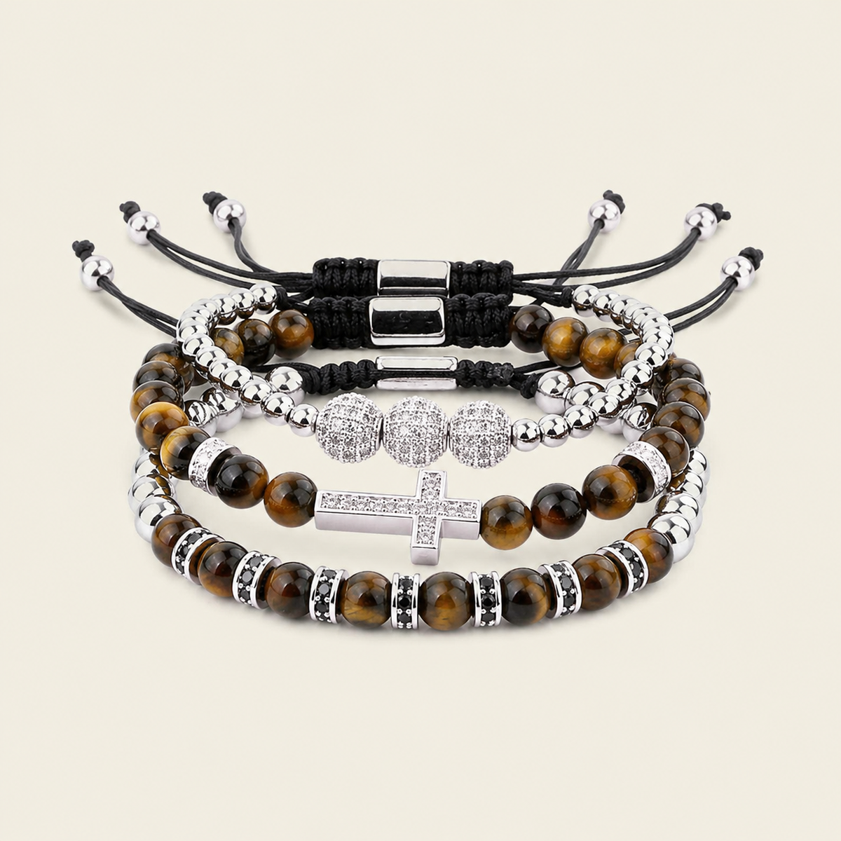 Four beaded stretch bracelets stacked together on a light beige background. The bracelets feature brown tiger's eye beads, silver-toned metal spacers, black cord wraps, and a silver-toned cross charm embellished with clear rhinestones.