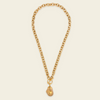 A gold chain necklace with a toggle clasp and a small, irregularly shaped gold pendant, displayed on a light cream background.