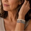 Woman wearing multiple bracelets on her wrist with a neutral background