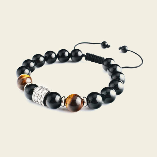 Black beaded bracelet with brown and silver accents on a beige background