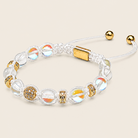 A beaded adjustable bracelet with clear round beads, iridescent beads, gold-toned spacer details, and a gold clasp on a white cord, shown on a light beige background.