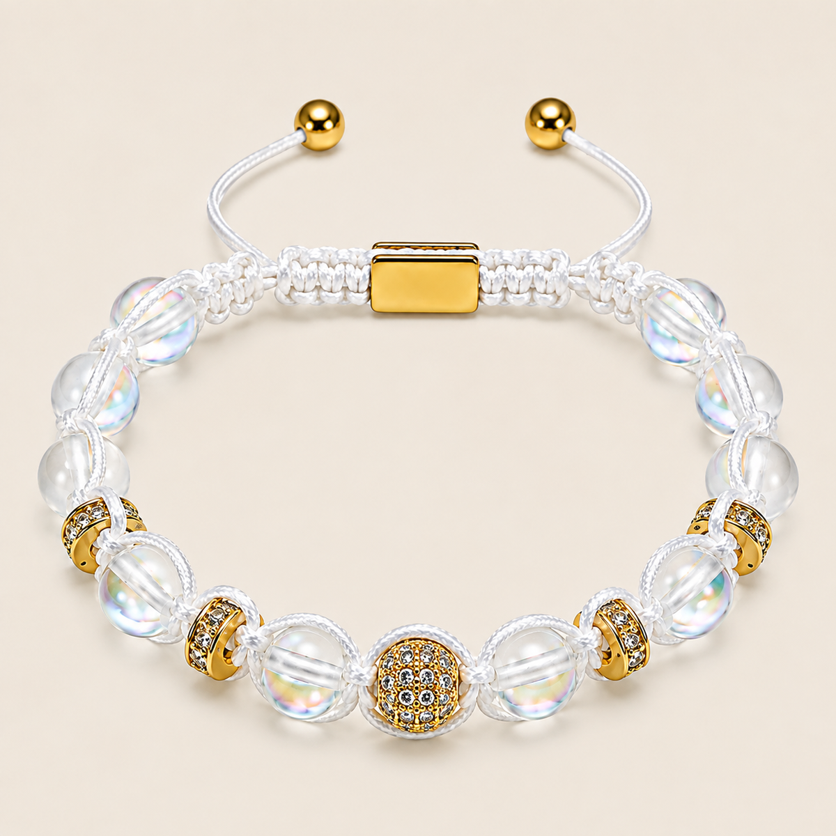 A white macrame bracelet with iridescent clear beads, gold spacer beads, and a central gold-plated square clasp, shown on a light beige background.