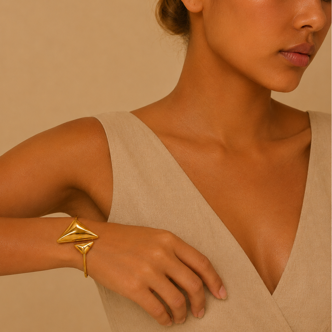 Woman wearing a gold bracelet on a beige background