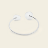 A minimalist silver-toned open cuff bangle bracelet with smooth, rounded disc-like ends, displayed on a solid light beige background.