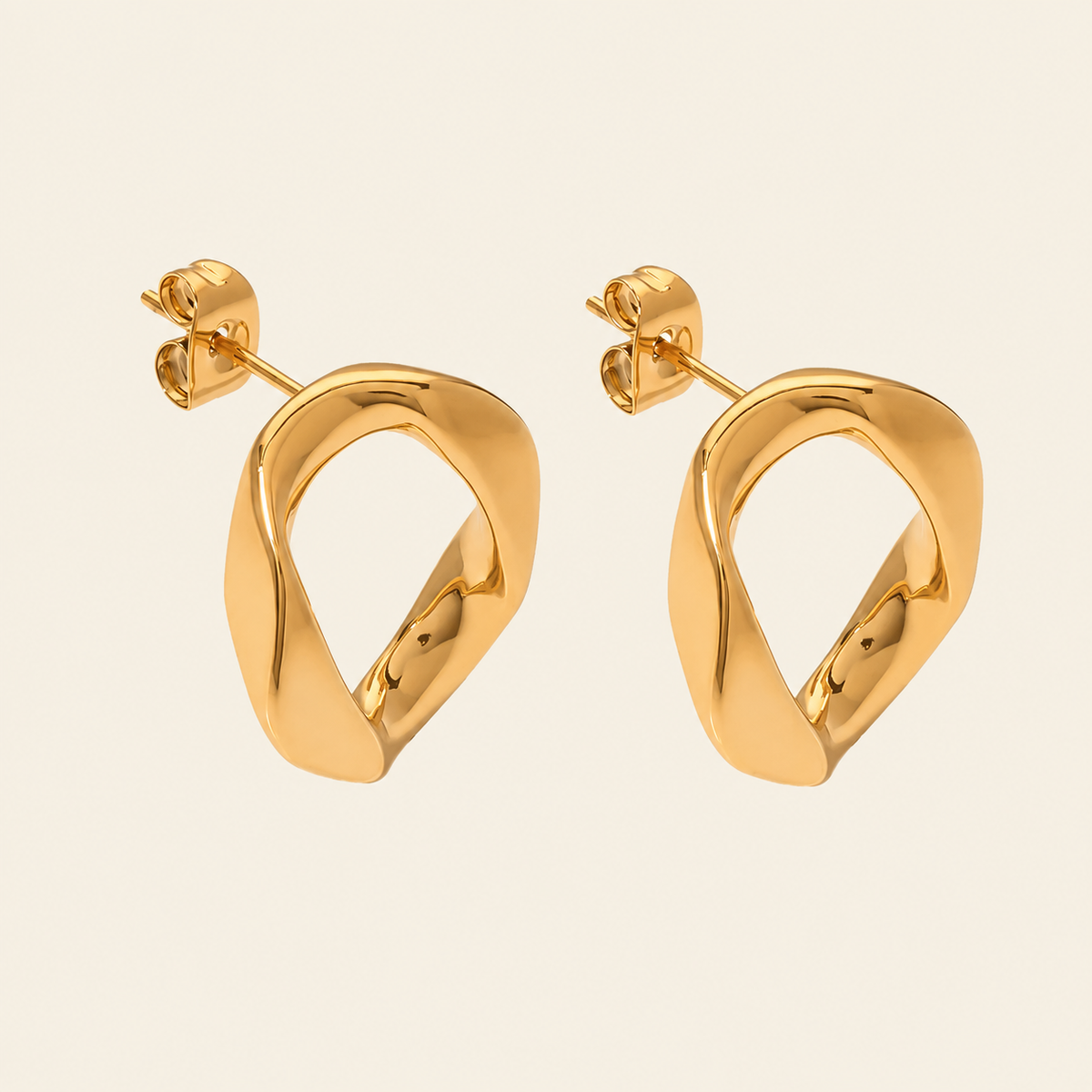 A pair of gold-toned abstract loop dangle earrings with a polished finish, displayed on a light cream background.