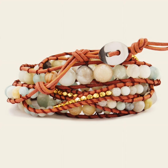 Multistrand bracelet with beads and leather wrap on a beige background