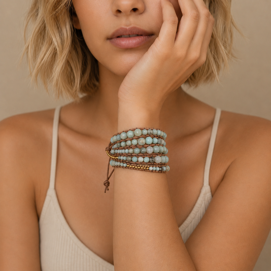 Woman wearing a stack of bracelets on her wrist against a neutral background