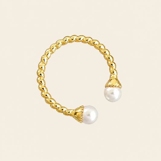 Gold ring with two pearls on a beige background