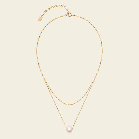 Gold necklace with a pearl pendant on a beige background