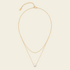 Gold necklace with a pearl pendant on a beige background