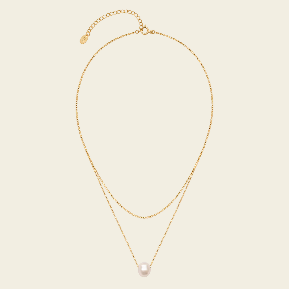 Gold necklace with a pearl pendant on a beige background