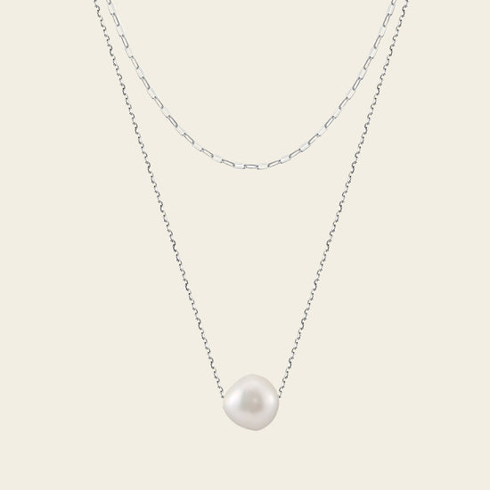 Pearl necklace on a thin chain against a light background