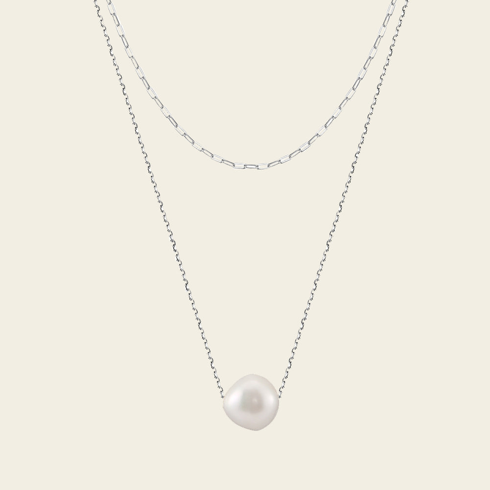 Pearl necklace on a thin chain against a light background