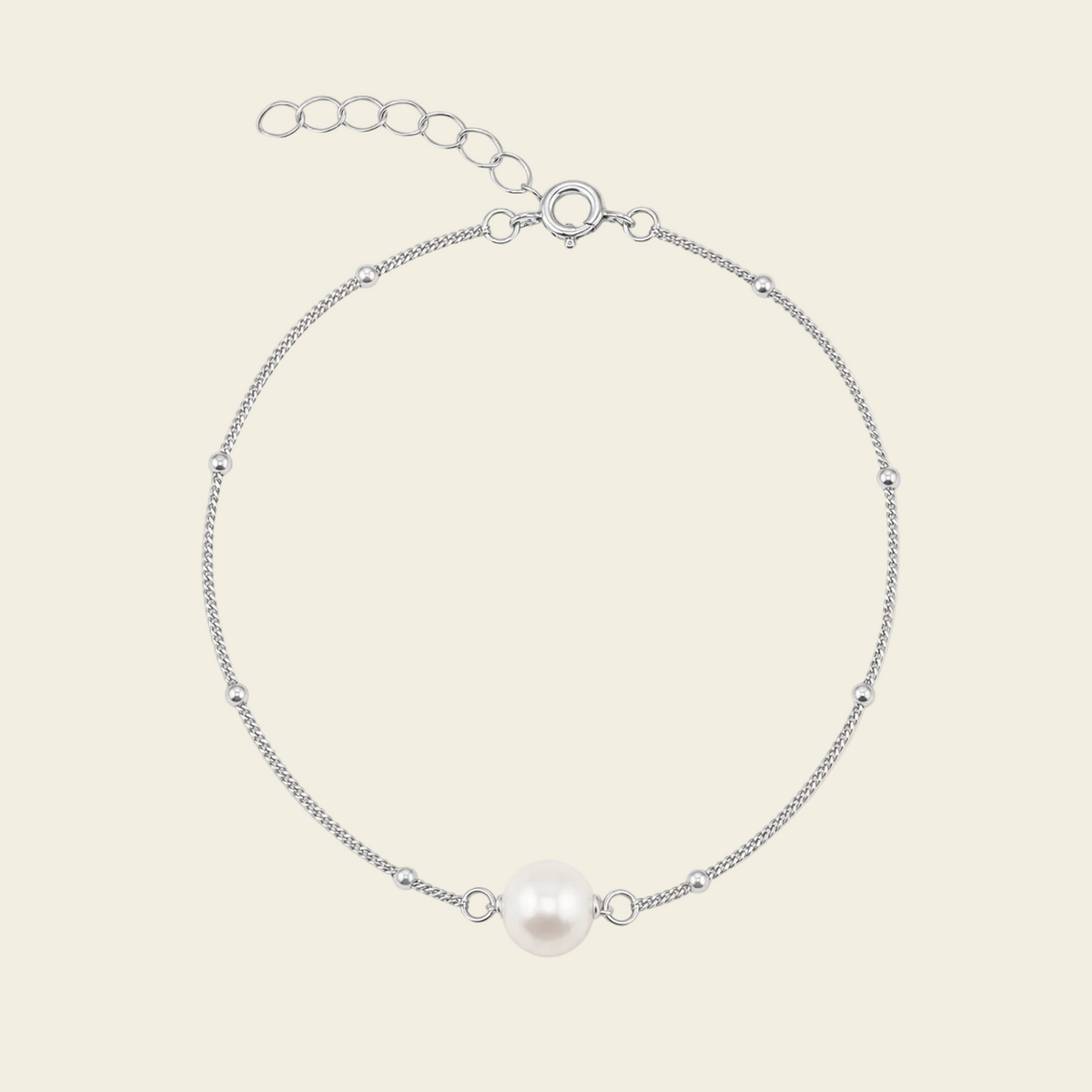 A delicate silver chain bracelet featuring a single white freshwater pearl at the center, displayed on a light beige background.