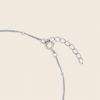Silver chain extender with a lobster clasp and oval link chain on a light beige background.