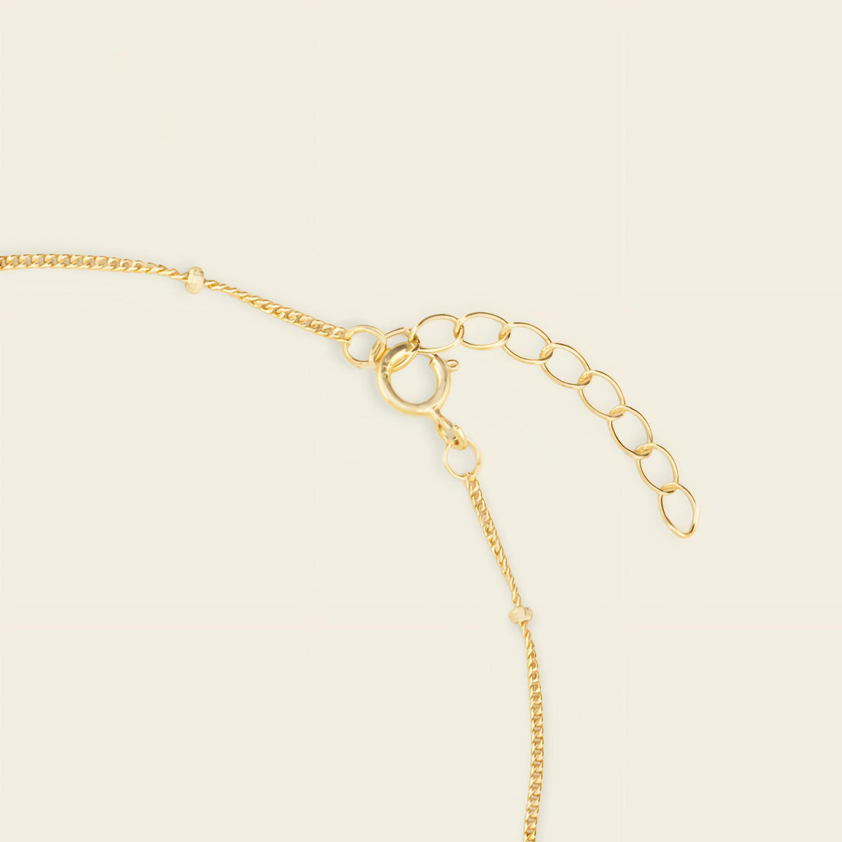 Gold chain necklace on a beige background