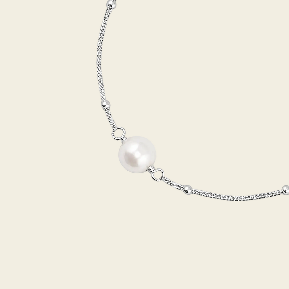 A delicate silver chain bracelet featuring a single lustrous white pearl bead at its center, displayed on a solid light beige background.