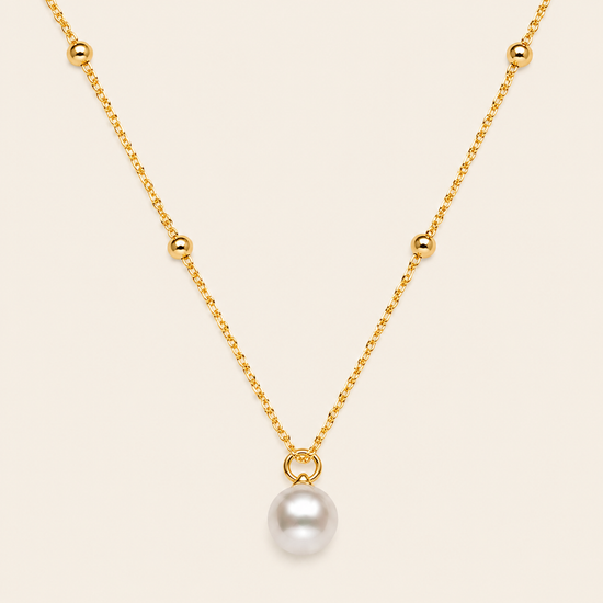 Gold necklace with a single pearl pendant on a beige background