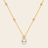 Gold necklace with a single pearl pendant on a beige background
