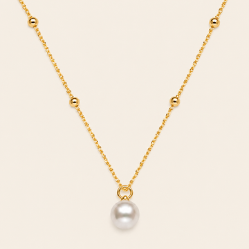 Gold necklace with a single pearl pendant on a beige background